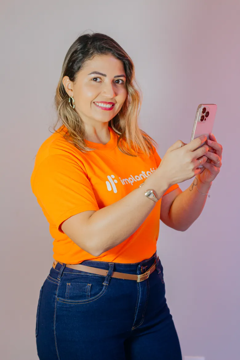 Alexandra, da Implanta Fácil, com o celular